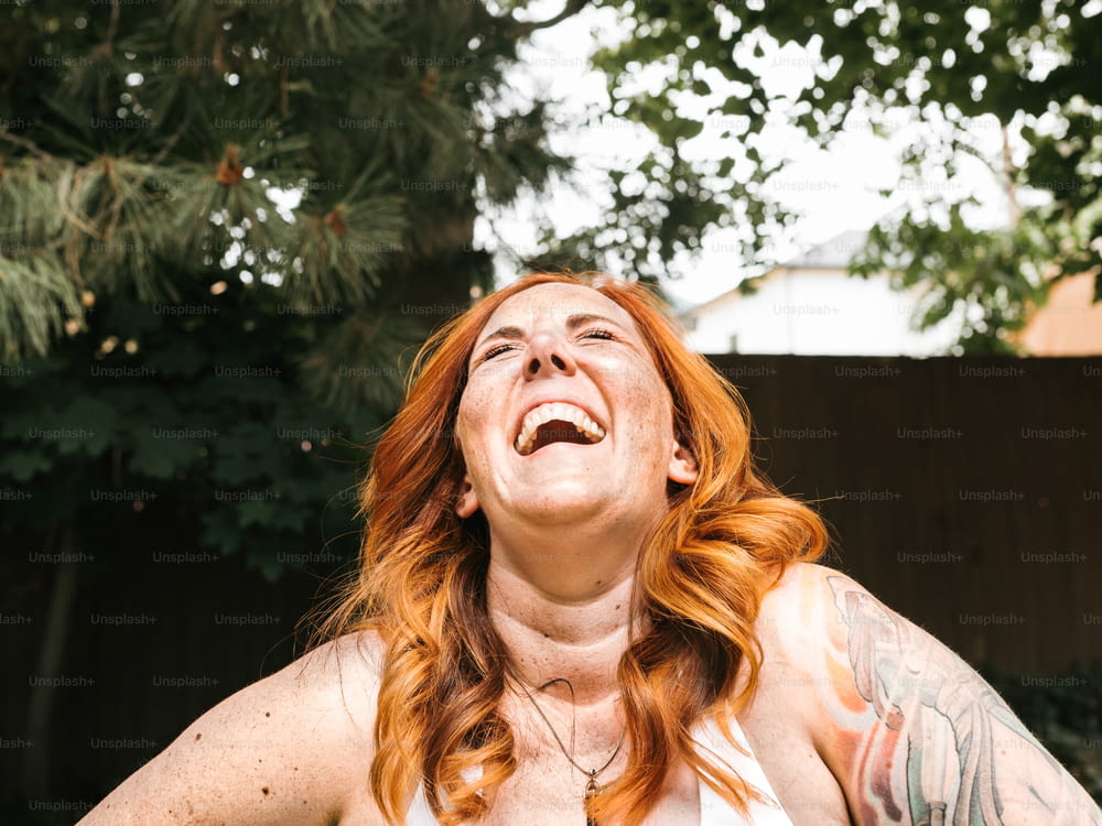 赤い髪と入れ墨をした女性が笑う