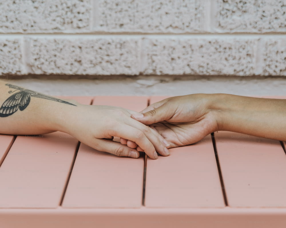 uma pessoa com uma tatuagem no braço sentada em um banco rosa