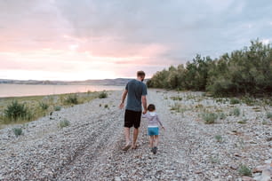 a man and a little girl walking down a gravel road