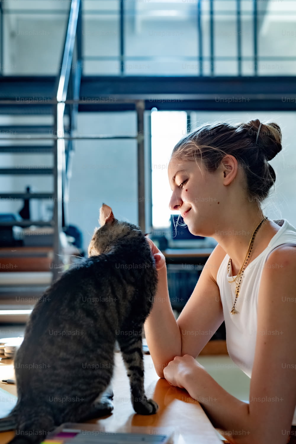 Una mujer sentada en una mesa acariciando a un gato
