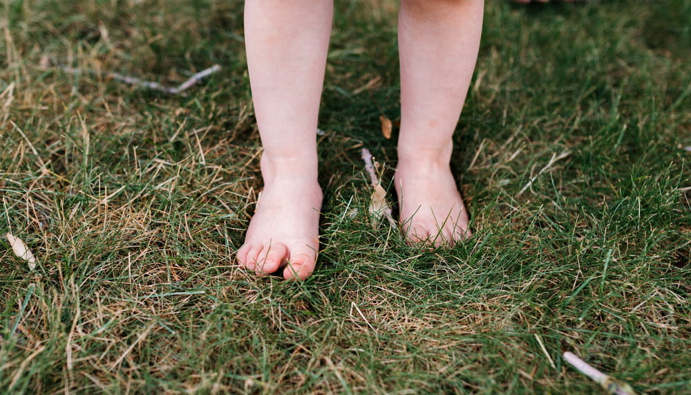 um close up dos pés descalços de uma pessoa na grama