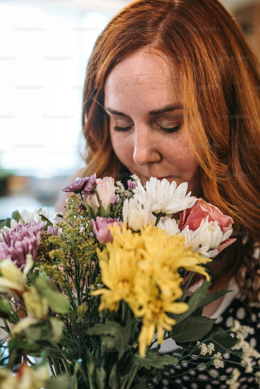 uma mulher cheirando um ramo de flores em um vaso