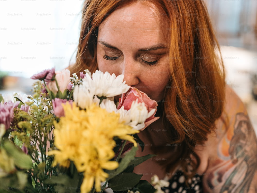 Una mujer oliendo un ramo de flores con los ojos cerrados