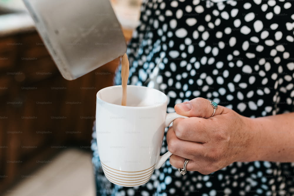 Eine Frau, die Kaffee in eine weiße Tasse gießt