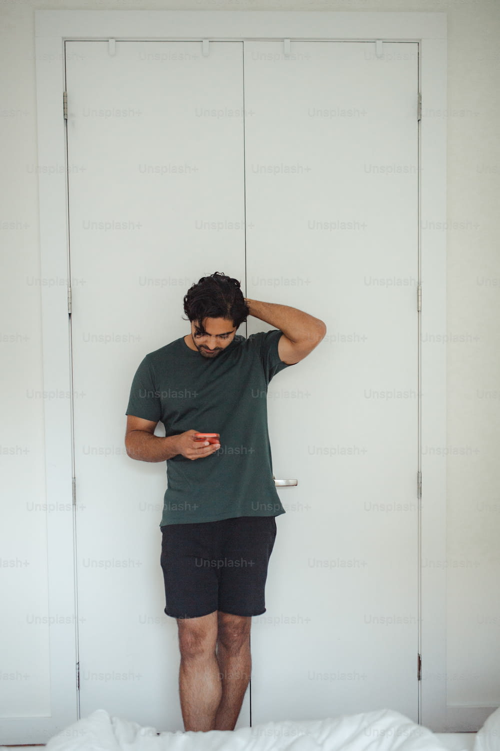 a man standing in front of a door looking at his cell phone