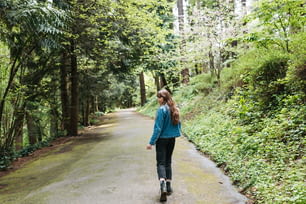 uma mulher caminhando por uma estrada na floresta