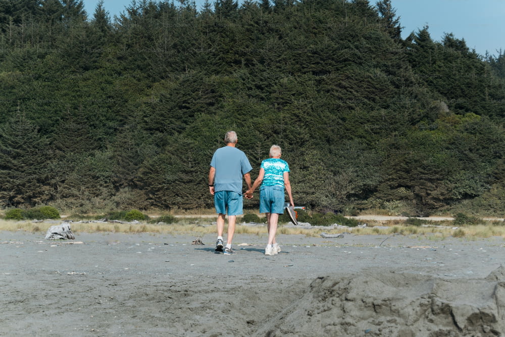 a man and a woman holding hands while standing on a beach
