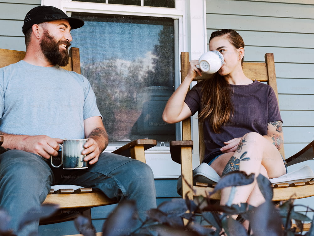 a man and a woman sitting on rocking chairs drinking coffee