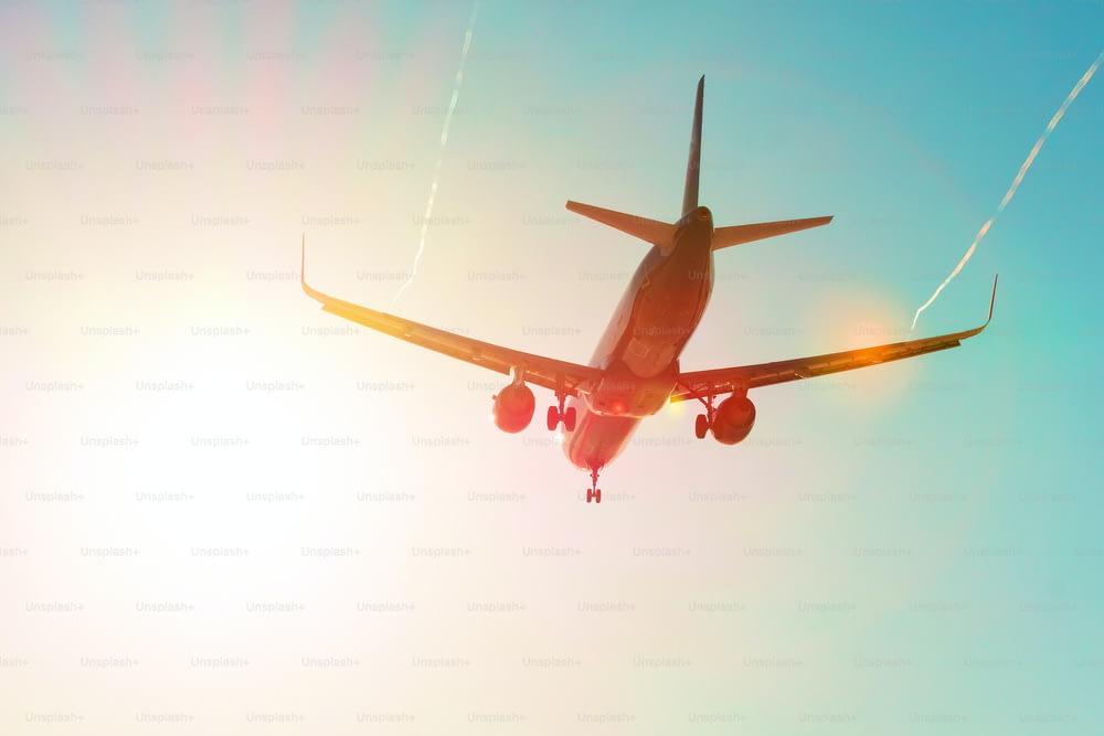 着陸時に虹色のグラデーションで太陽のまぶしさの近くを飛行する旅客機は、蒸気ジェットの渦の翼で飛行します