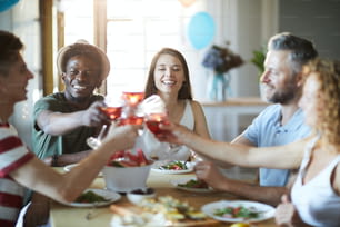 Glückliche interkulturelle Freunde versammelt sich am Tisch zur Weihnachtsfeier zu Hause