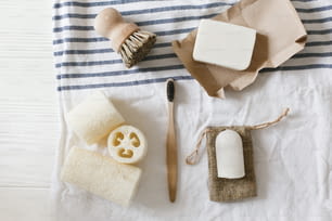 zero waste concept. natural plastic free luffa, bamboo toothbrush, brush, coconut soap and crystal deodorant, for hygiene cleaning on towel, eco bathroom essentials. sustainable lifestyle