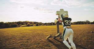 Young American football player doing tackles and defensive drills outside on a sports field in the late afternoon