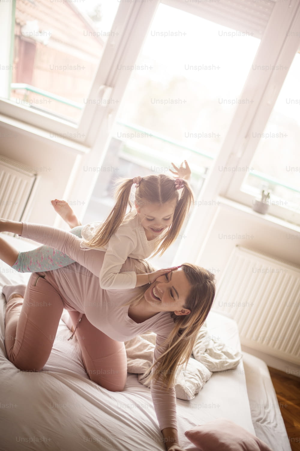 Let's start playing in the morning. Mother and daughter playing on bed.