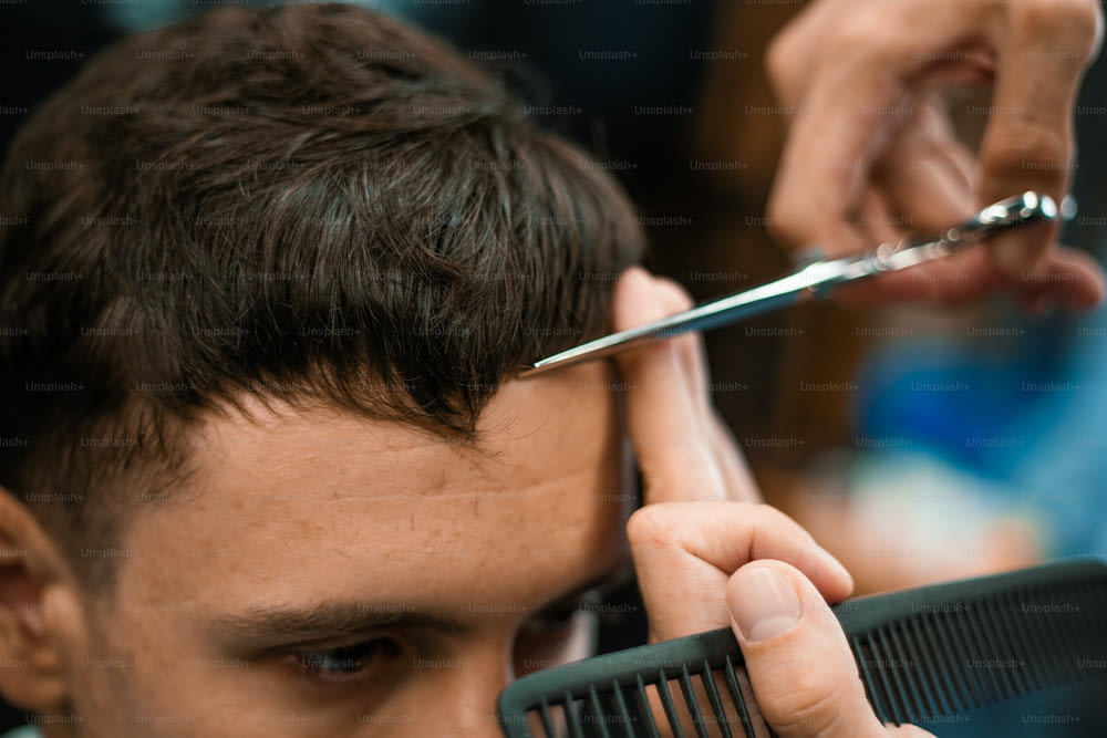 Barbershop. Close-up of man haircut, master does the hair styling in barber shop. Close-up, master Barber does the hairstyle and styling with scissors. Concept Barbershop.