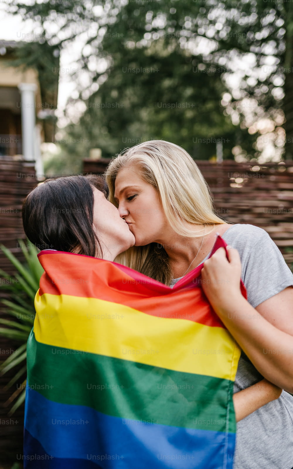 LGBT orgulhoso casal lésbico beijando segurando bandeira do arco-íris gay