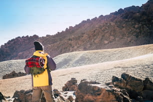 Outdoor leisure activity people with standing man and backpack hiking the mountains alone - travel and discover exploring the workd concept - back view of traveler in the outdoors