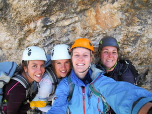 Vista di quattro alpiniste che festeggiano sulla cima della montagna scattando una foto di gruppo