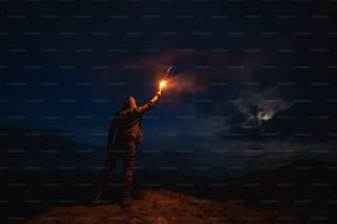 L’homme avec un bâton de feu d’artifice debout sur la montagne nocturne