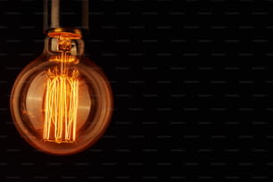 コピー スペースと黒い背景にビンテージ電球。光るエジソン電球