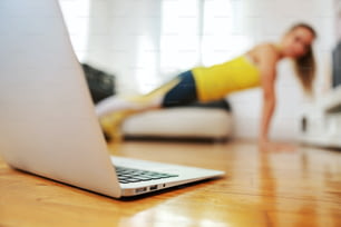 Fitness instructor doing pushups at home and having online class with her students.