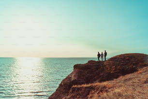 Die drei Personen, die auf dem Berggipfel in der Nähe des Meeres stehen