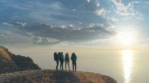Die vier Menschen, die auf dem Berggipfel gegen die Meereslandschaft stehen