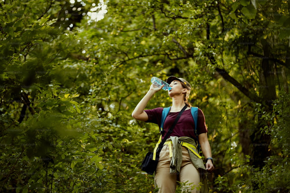 Jeune femme se rafraîchissant avec de l’eau lors d’une randonnée dans la nature,