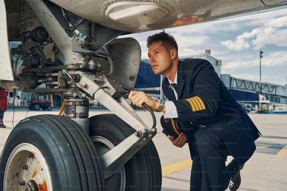 Jeune aviateur concentré en uniforme effectuant une inspection visuelle d’un véhicule aérien