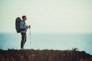 Der Reisende mit Rucksack steht auf dem Berggipfel über dem Meer