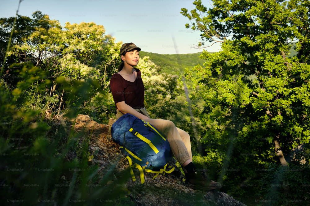 Carefree woman taking a break and relaxing with eyes closed while hiking in nature.