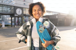 Young attractive skateboarder in casualwear looking at you with toothy smile