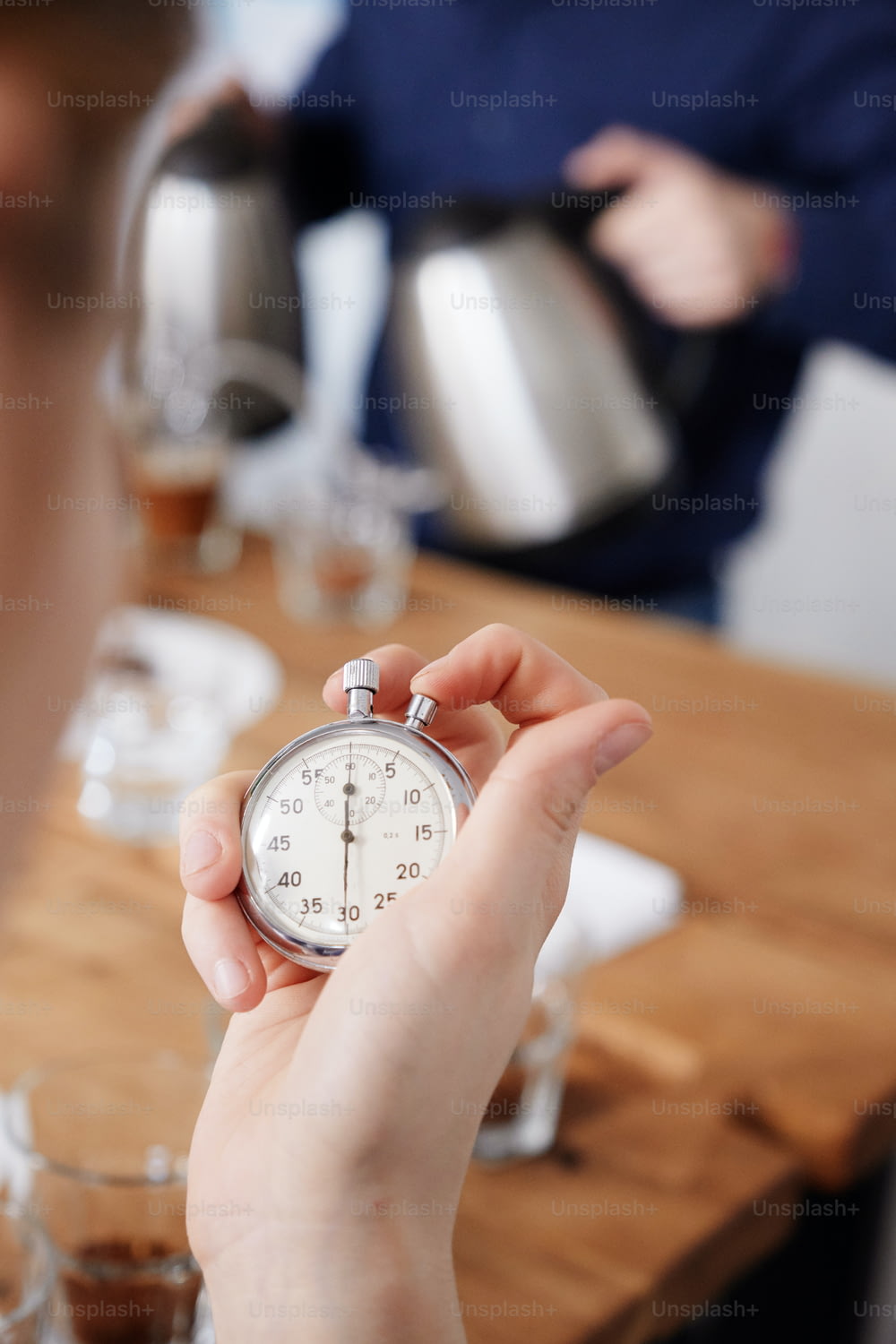 Primo piano della donna che tiene il cronometro, misurando il tempo per la preparazione del caffè fresco in tazze