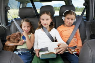 three young girls sitting in the back of a car