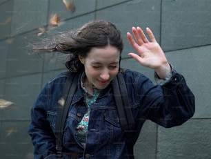 a woman in a jean jacket is waving her hands