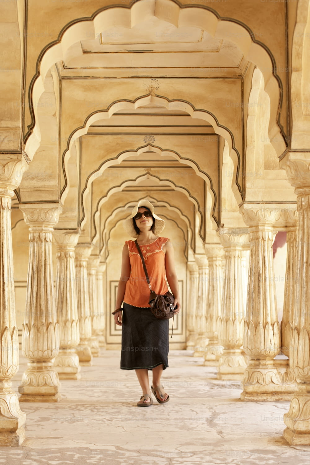 Une femme en chemise orange et jupe noire debout dans un immeuble
