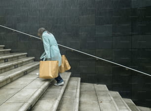Una mujer bajando unas escaleras cargando bolsas de compras