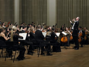 um maestro e orquestra em uma grande sala