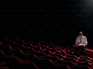 a man in a tie sitting in a theater