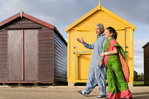 a man and a woman walking in front of a yellow building