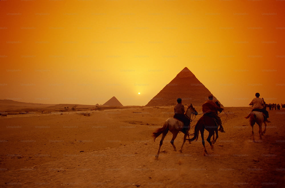 Un grupo de personas montando a caballo frente a las pirámides