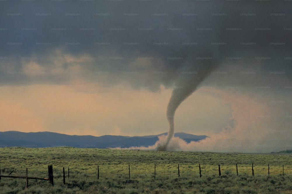a large tornado is coming out of a field