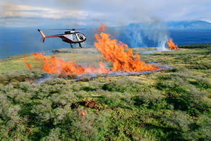 um helicóptero sobrevoando um campo em chamas