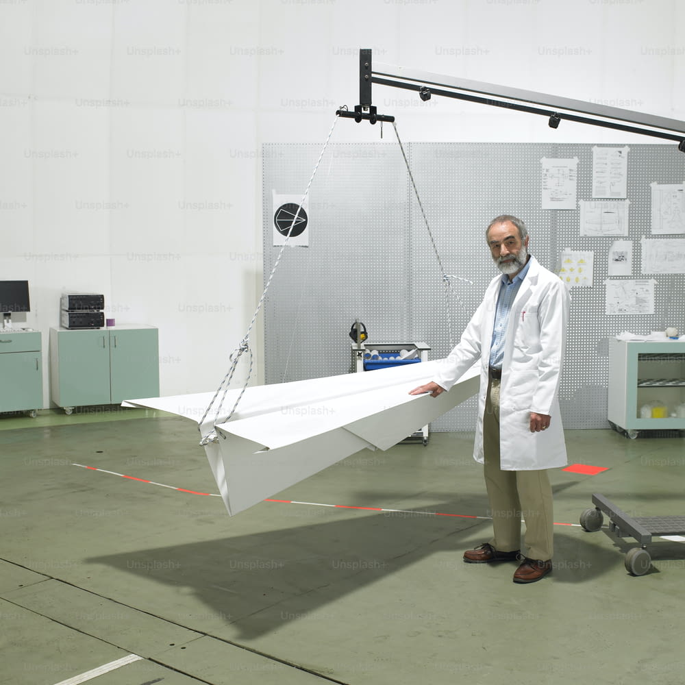 Un hombre con una bata de laboratorio sosteniendo un avión de papel