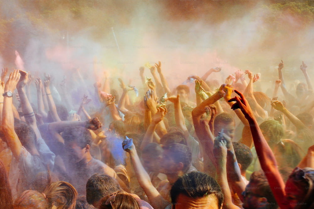 persone felici che fanno festa sotto una nuvola di polvere colorata