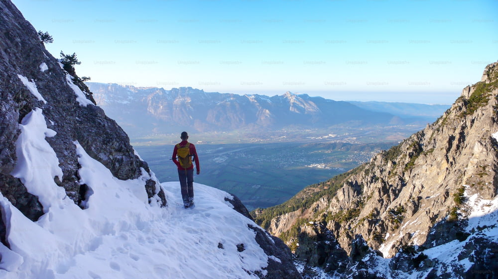 escursionista maschio su un sentiero escursionistico all'inizio dell'inverno nelle montagne del Liechtenstein con una splendida vista sulla valle del Reno sotto di lui