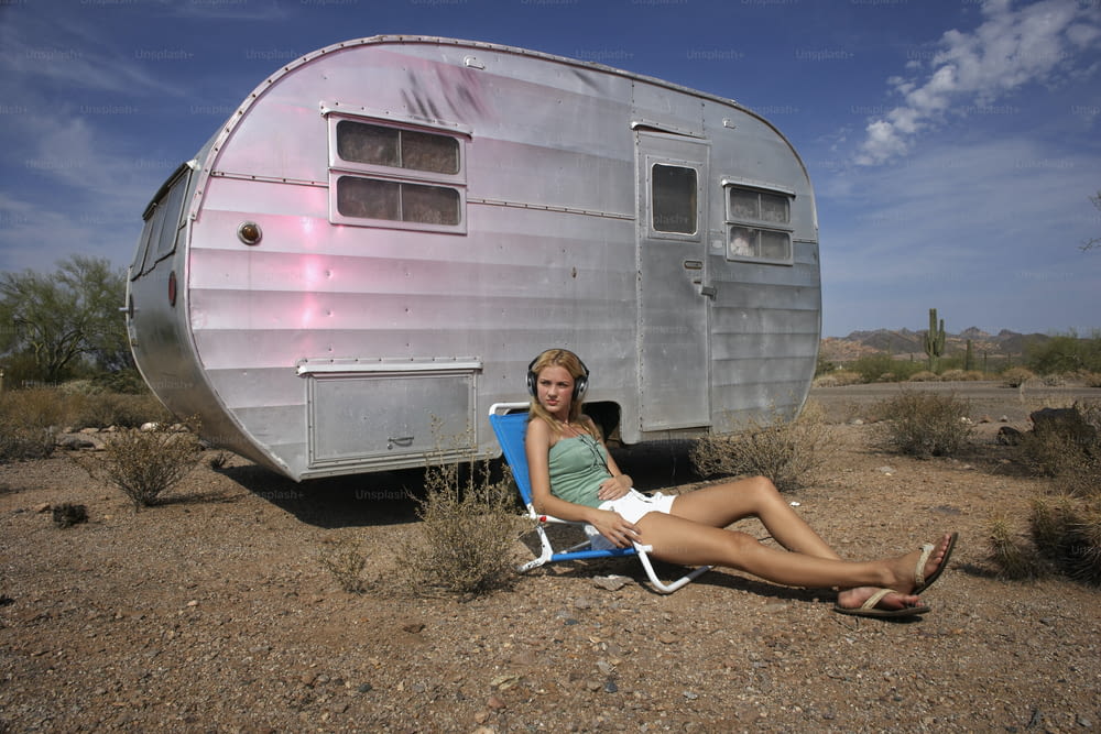 uma mulher sentada em uma cadeira em frente a um trailer