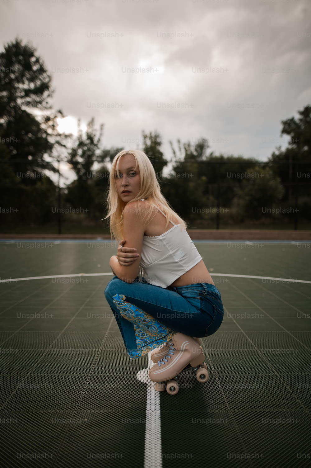 a woman sitting on top of a skateboard on a court