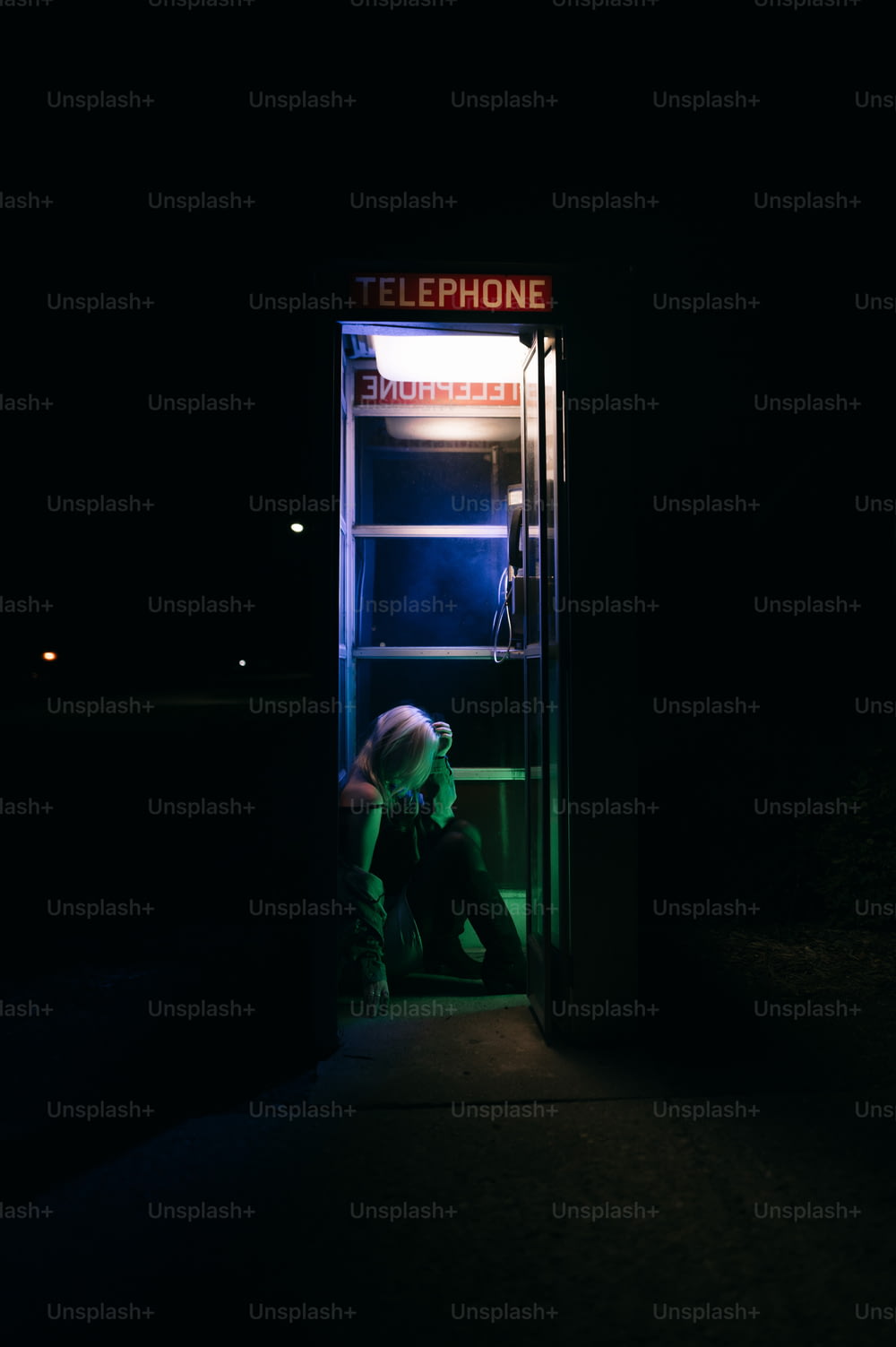 a person sitting in a phone booth at night