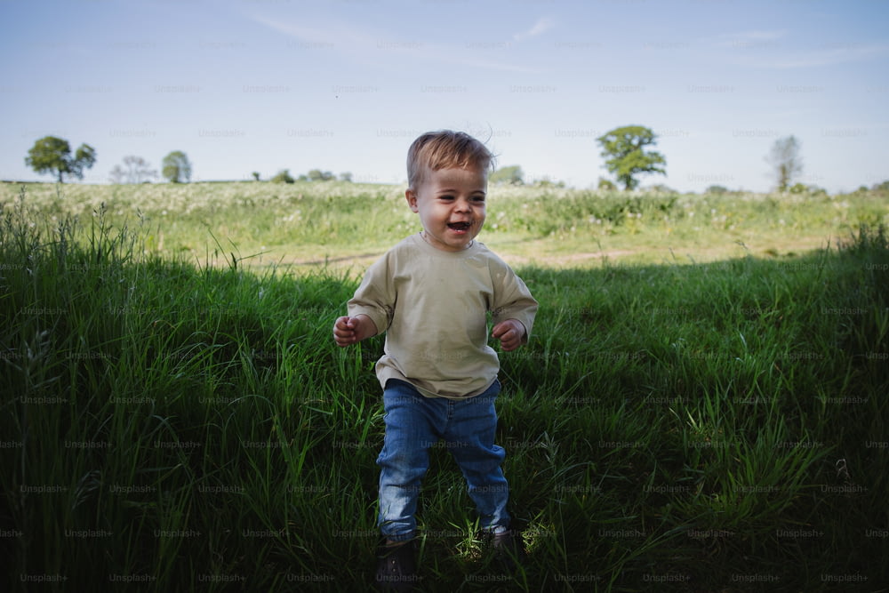 a little boy running through a field of tall grass