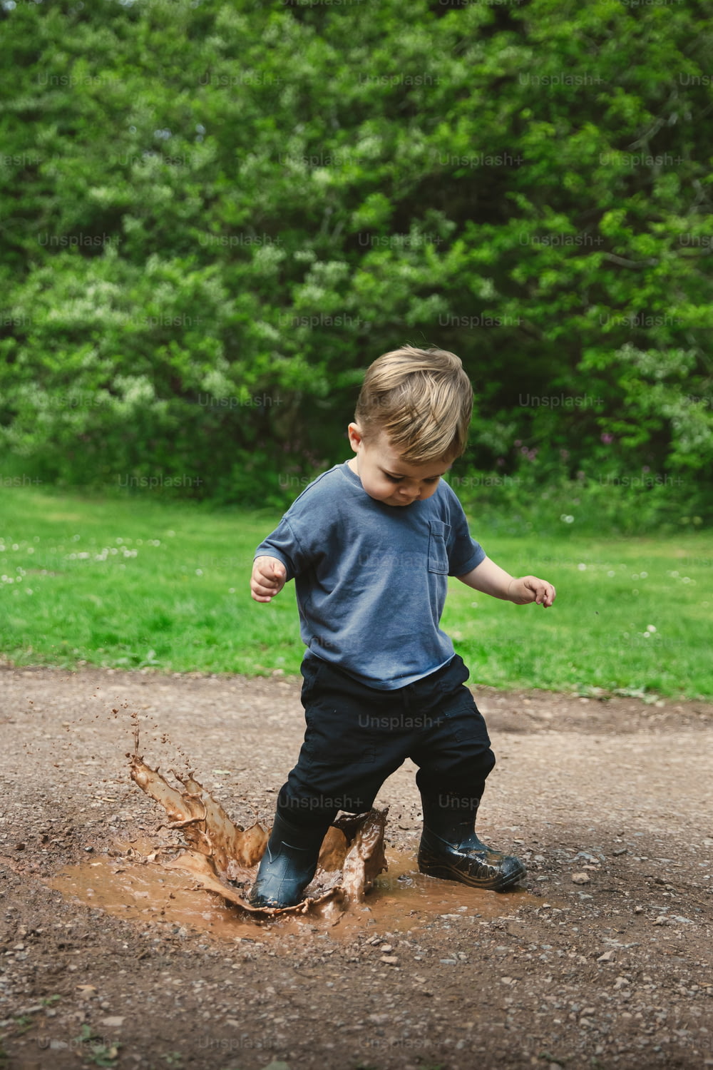 Un giovane ragazzo che gioca in una pozzanghera di fango